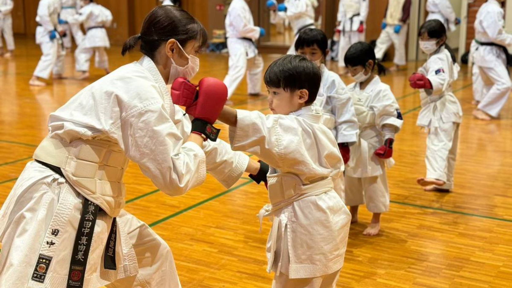 指導員が初心者の子どもに組手を丁寧に指導する練習風景