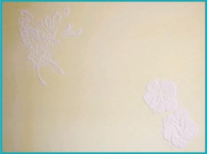 黄色い壁に白漆喰で盛られた蝶と花。